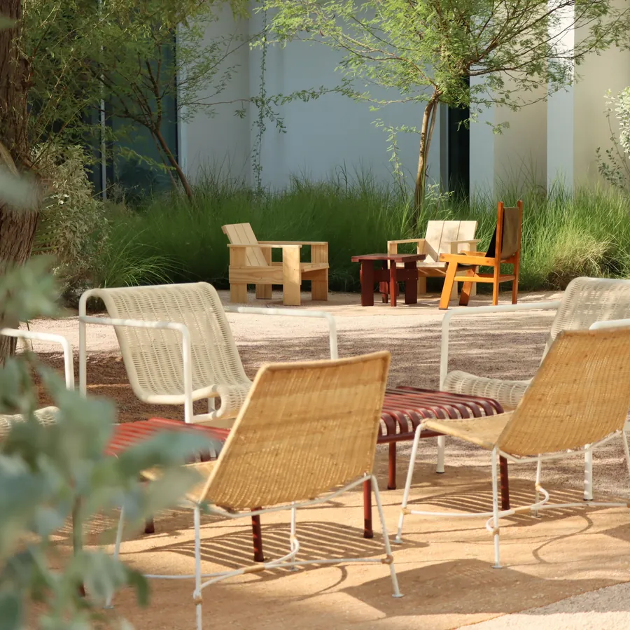 Woven lounge chairs set out under the trees in the Paus courtyard
