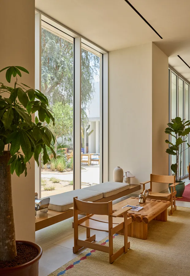 A long window seat and reading table beside full height glass at Paus